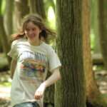 A teenager smiling near a tree.