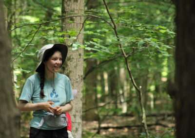 A teenager standing by a tree and smiling.