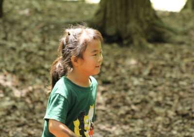 A young girl in the forest with sunshine on her face.