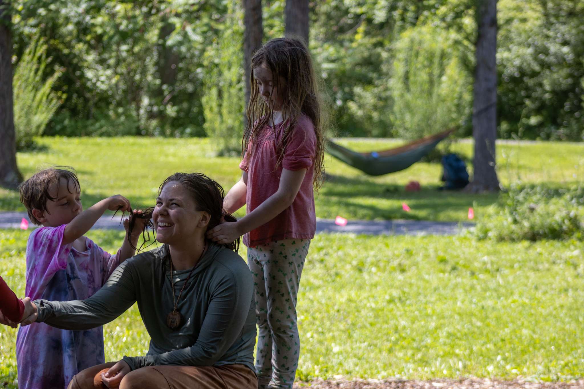An instructor holding a campers hand while hair is being braided by two other campers.