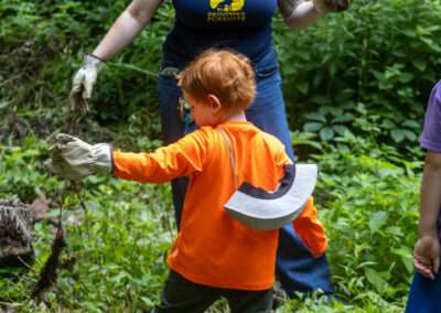 Young camper holding a weed that was just pulled from ground.