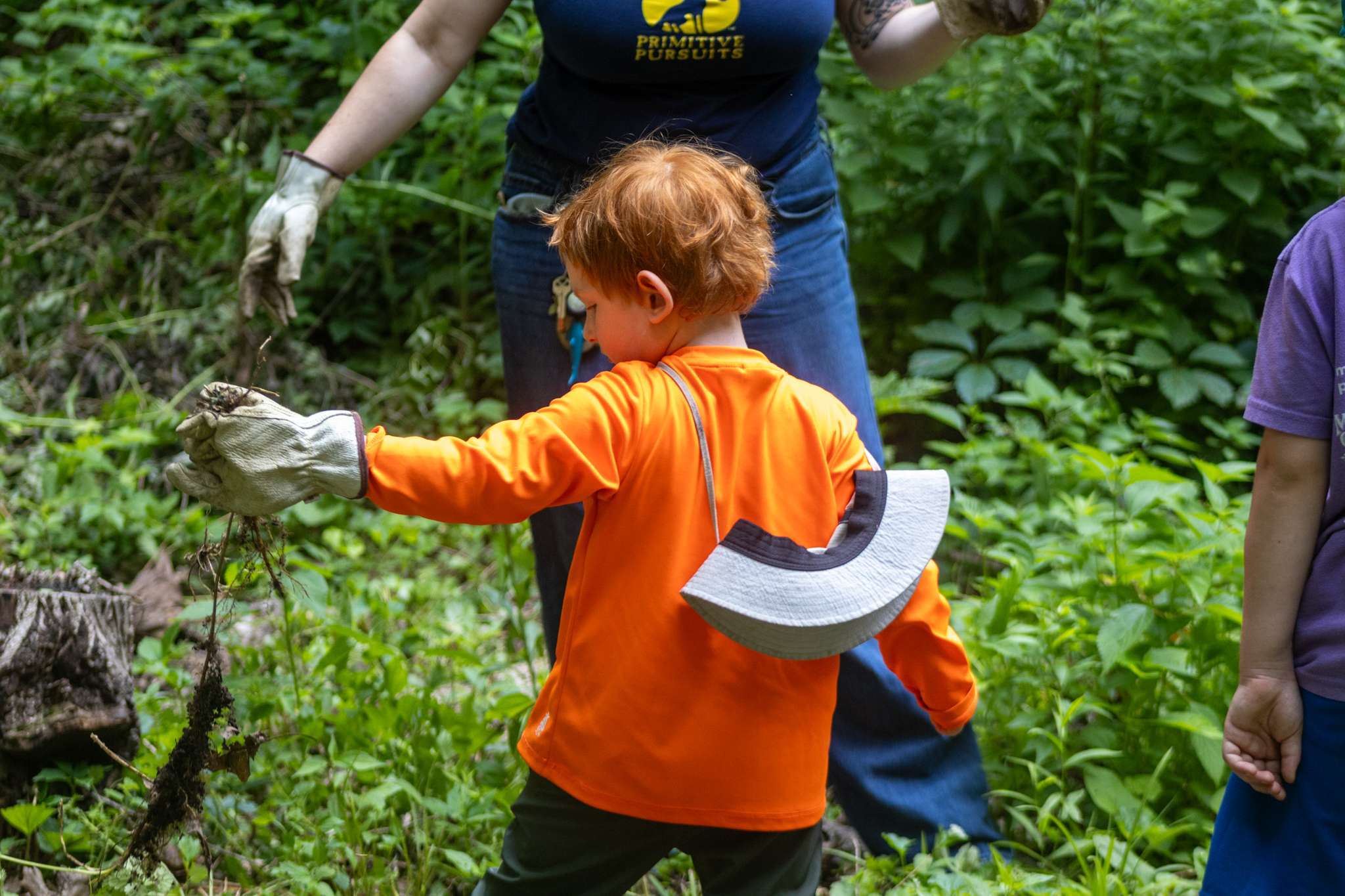 Young camper holding a weed that was just pulled from ground.