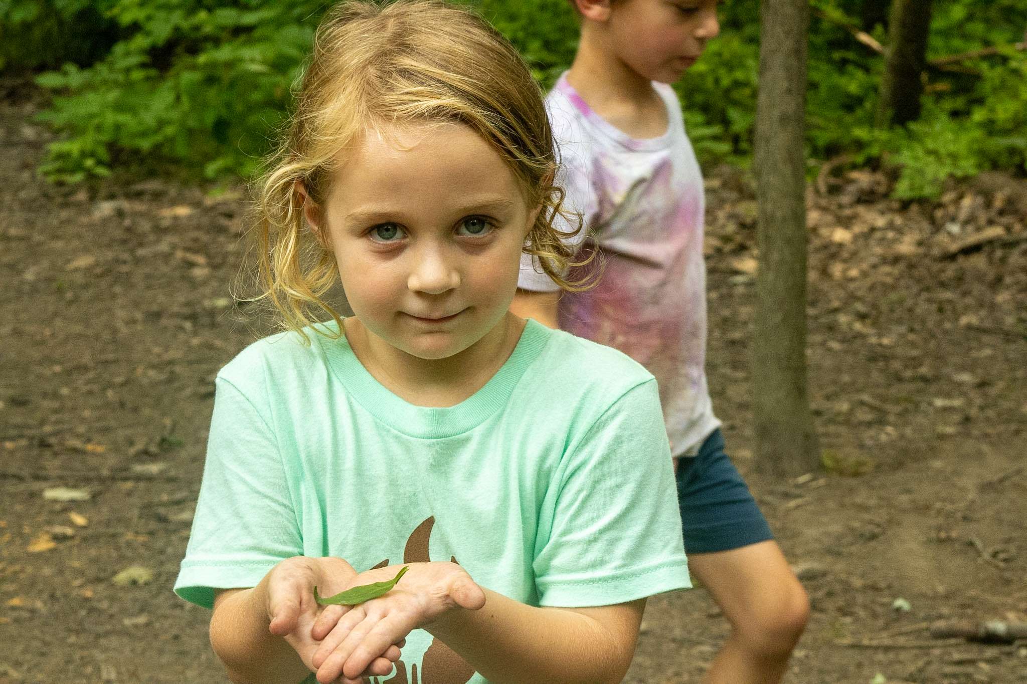 Younger camper holding up a leaf for the camera.