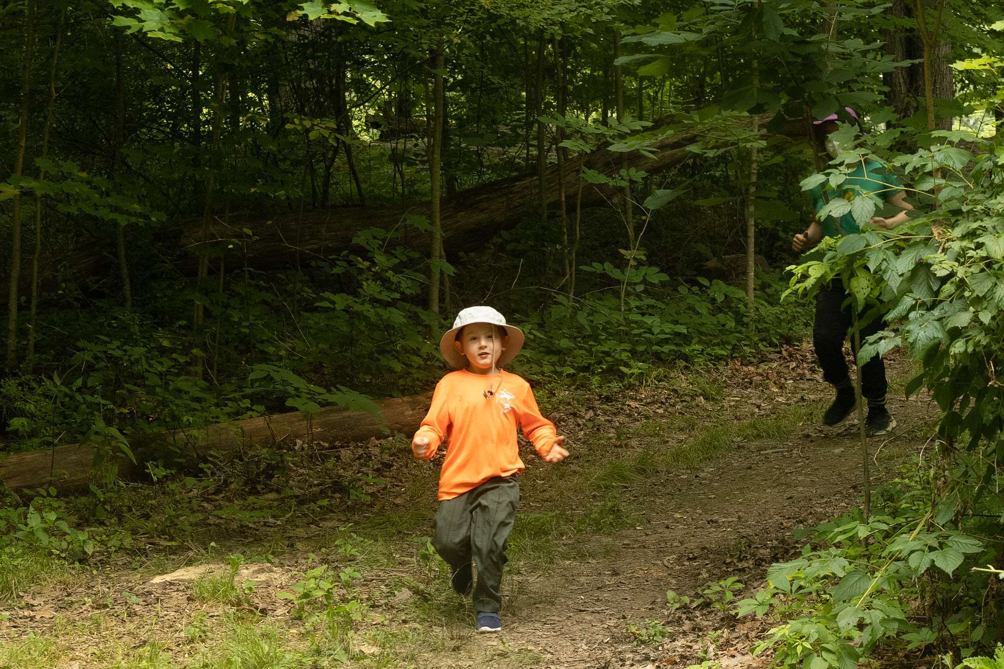 Young camper running down a hill in the forest.
