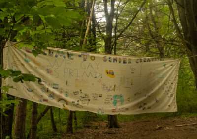 A banner made by campers, hung up between two trees.