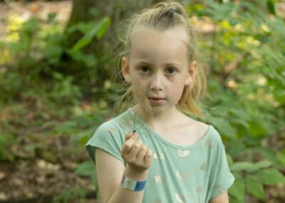A younger camper holding up a cool leaf for the camera.