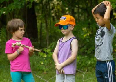 Three younger campers standing in a grassy field talking.