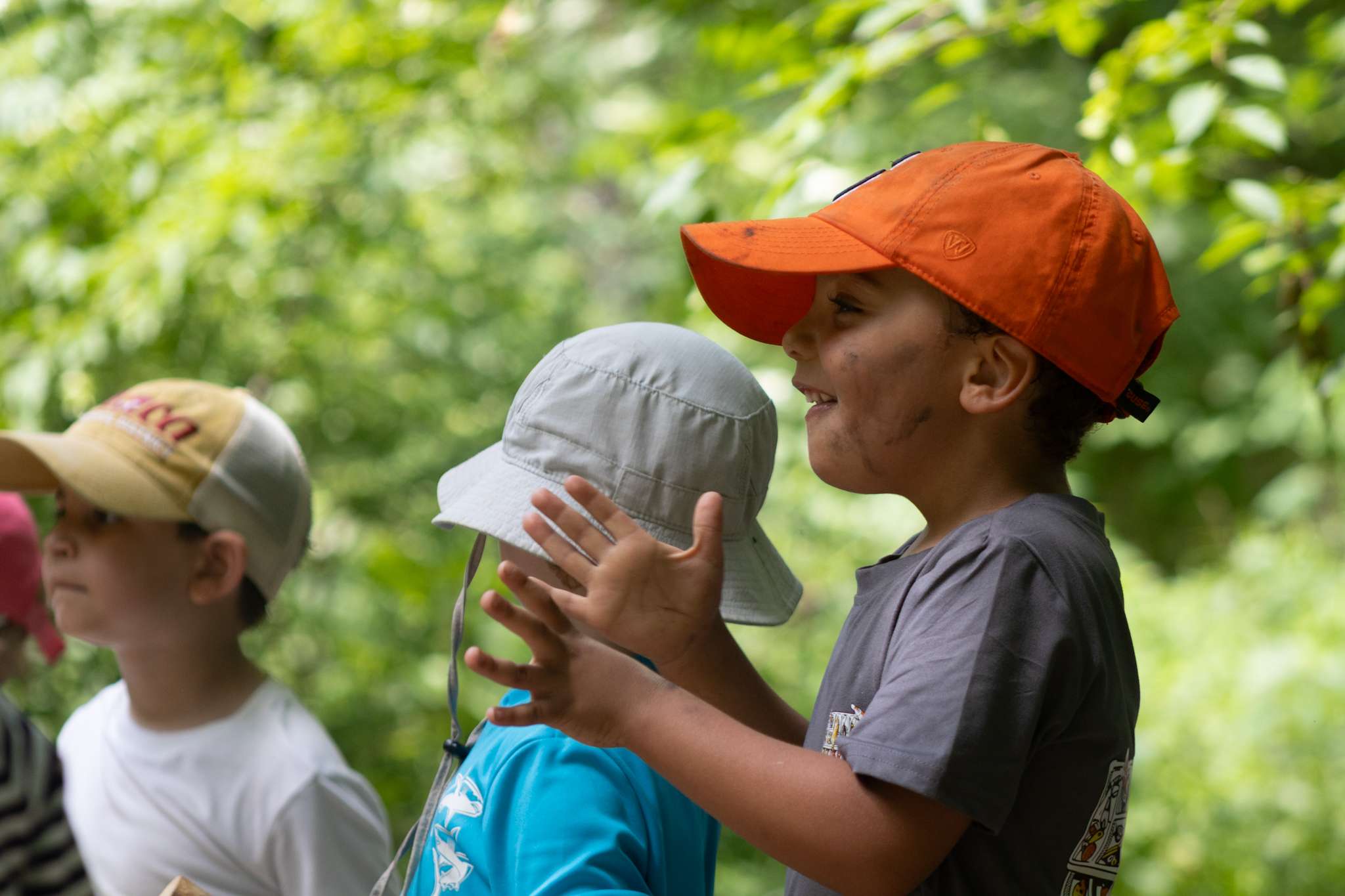 A young child clapping his hands in excitement, with other children are also visible in the background.