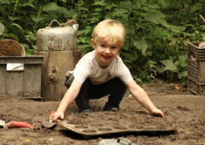 Younger camper holding a muffin tin filled with sand from the sandbox.