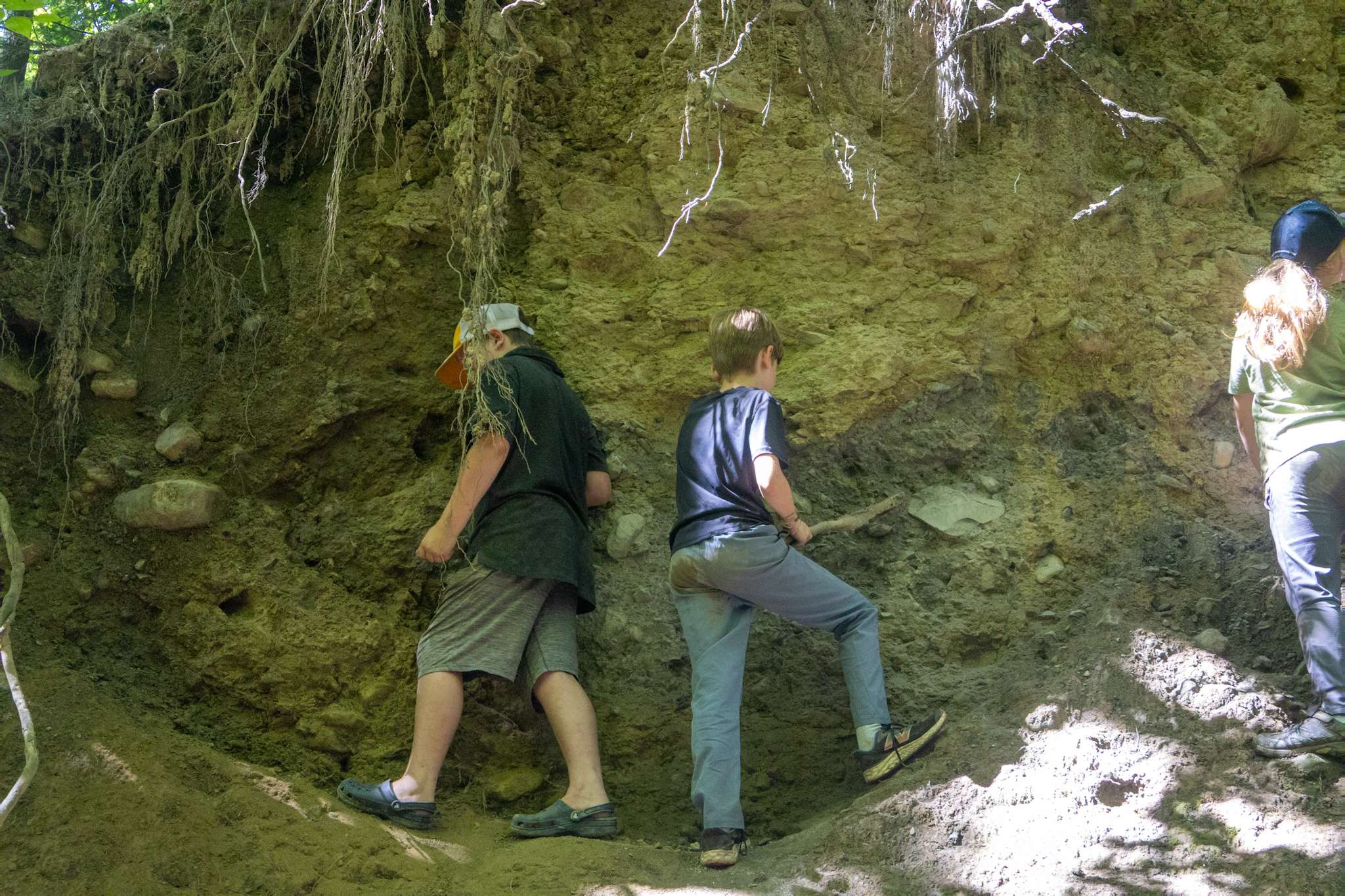 IMG_9947 Two older campers standing against a cliff, searching for pieces of clay.