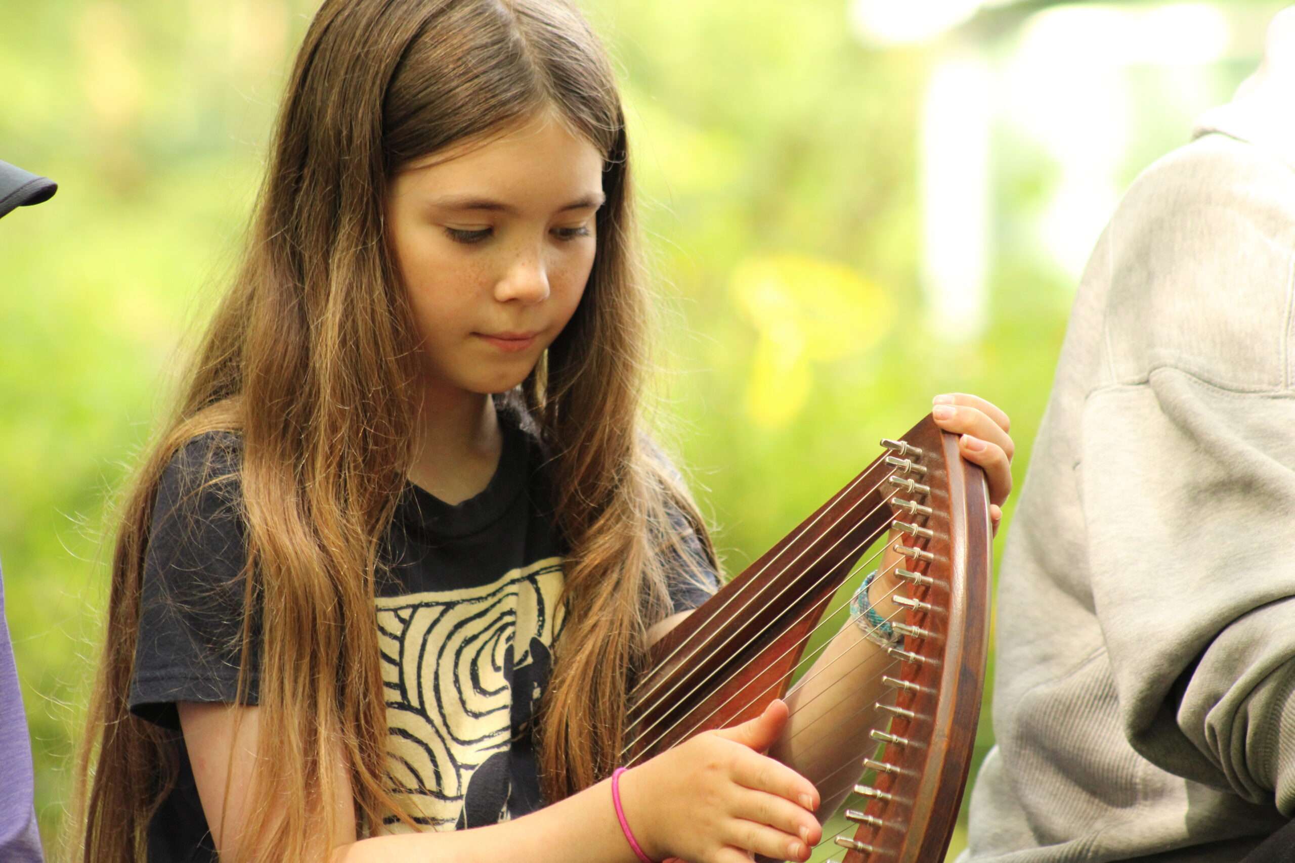 camper playing a musical instrument outside at camp