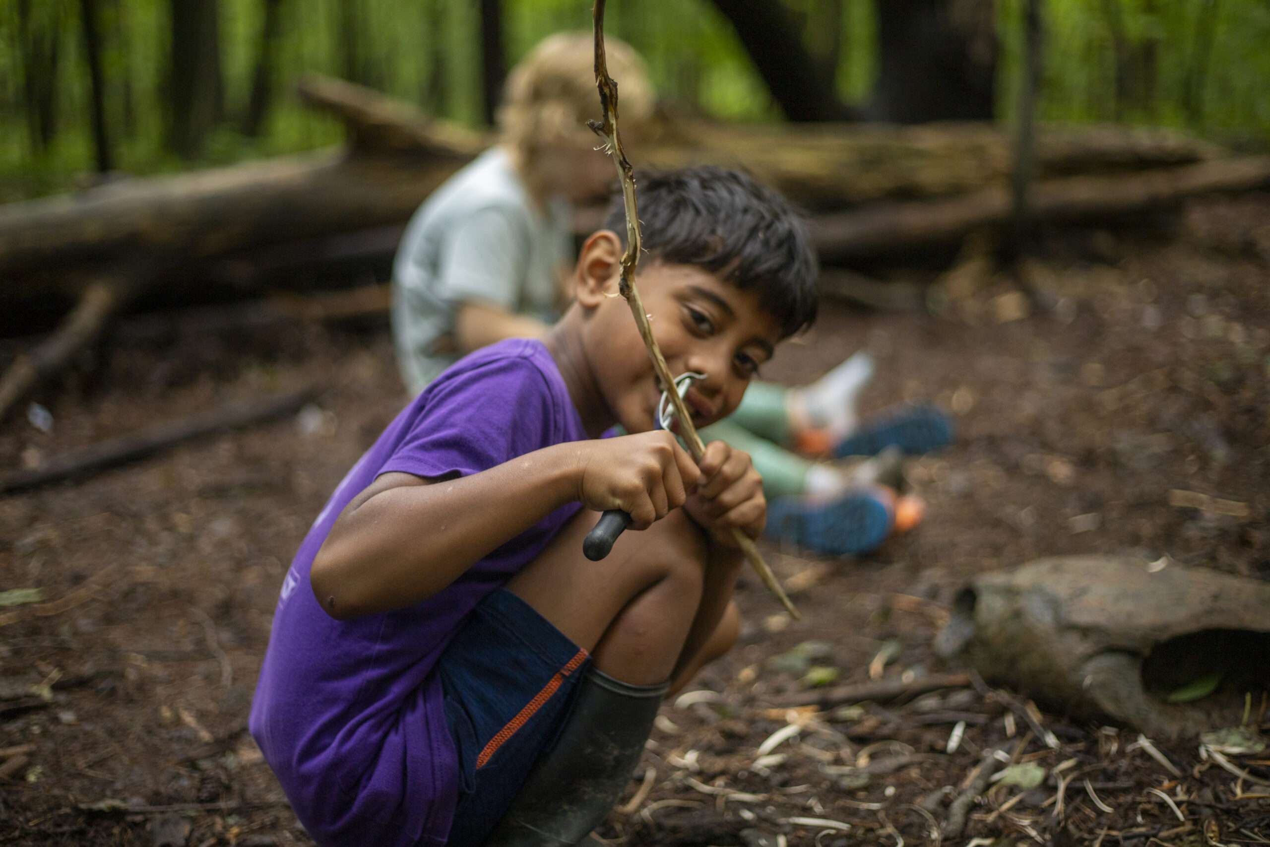 camper smiling up at the camera while practicing their carving skills